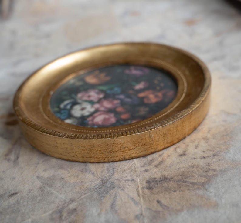 Side profile angle of the round gold frame lying flat, showcasing the thick wooden rim and gilded finish.