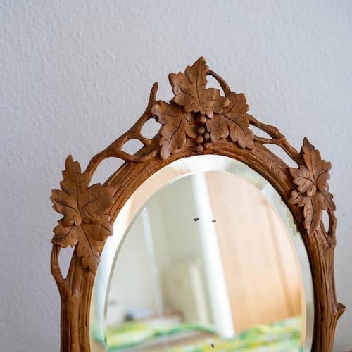 Miroir forêt-noire Miroir ovale ancien dans un cadre Adirondack avec des feuilles de vigne sculptées, des branches de vigne Dessus de table en bois sculpté biseauté
