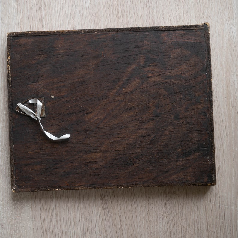May include: A dark brown wooden frame with a white piece of tape attached to the top left corner.