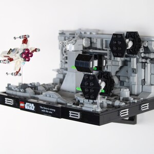 Puede incluir: Un expositor LEGO Star Wars negro con un caza X-Wing blanco y rojo y una cita de la película: "La Fuerza es fuerte en este."