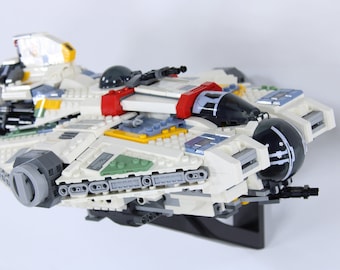 May include: A white, red, yellow and blue Lego spaceship with a black cockpit and a black and white design on the side.
