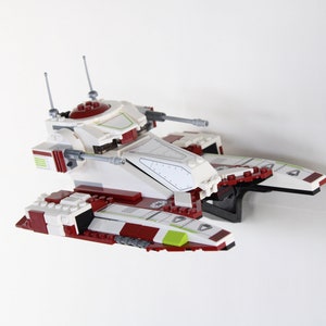 May include: A white and red Lego Star Wars Republic Gunship with green accents. The ship has two cannons on the top and two on the sides. The ship is in flight.