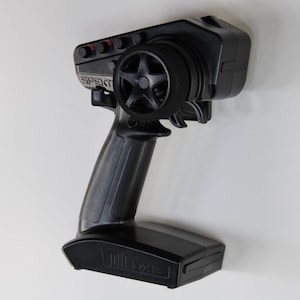 May include: Black remote control with a Spektrum logo and a large black knob. The remote control has a black trigger and a black handle.