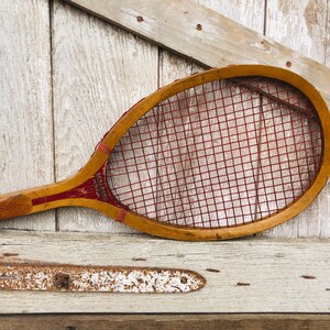 May include: A vintage wooden tennis racket with red stringing and the text "SPALDING J.T.R.IMP" on the handle.