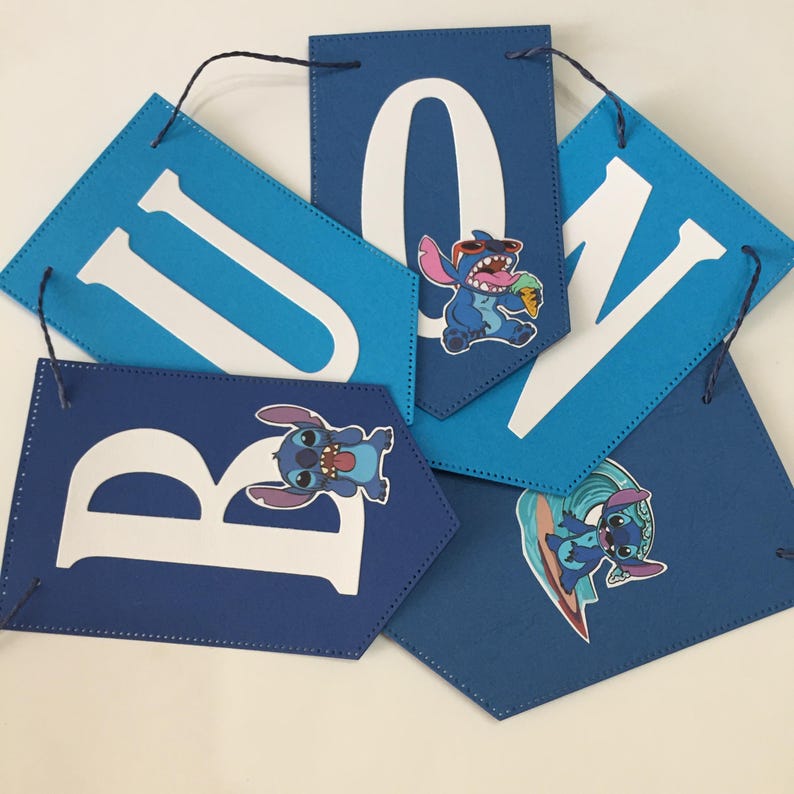 K&ouml;nnte beinhalten: Blaue und wei&szlig;e Filz-Girlande mit dem Wort "BUBU" in wei&szlig;en Buchstaben. Jeder Buchstabe hat einen anderen Stitch-Charakter aus dem Disney-Film Lilo & Stitch.