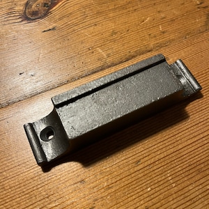 May include: A black metal door handle with a rectangular shape and a single screw hole. The handle has a smooth, slightly textured surface.