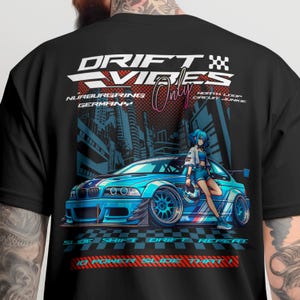 May include: Black t-shirt with a graphic of a blue sports car and anime-style character. Text includes "DRIFT VIBES Only" and "Nurburgring Germany". Additional text at the bottom reads "SLIDE SHIFT DRIFT REPEAT".