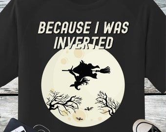 以下が含まれることがあります： 「Because I was inverted」というテキストと、満月を背景にほうきに乗って飛んでいる魔女のグラフィックが描かれた黒いTシャツ。魔女の周りをコウモリが飛んでいる。