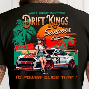 May include: Black t-shirt featuring a graphic of a white and red race car with the text "Drift Kings Sonoma California". The design includes an anime-style illustration of a person and palm trees. The text "I'D POWER-SLIDE THAT!" is also included.