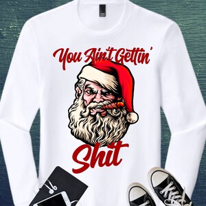 May include: White long-sleeve shirt featuring a graphic of Santa Claus with a cigar, wearing a red and white hat. The text "You Ain't Gettin' Shit" is printed above and below the Santa illustration in red.