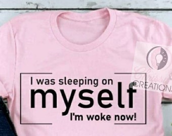 Pode incluir: Camiseta rosa com texto preto que diz "I was sleeping on myself I'm woke now!"