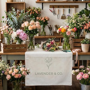 May include: A flower shop display featuring various bouquets of fresh flowers in glass vases and wooden crates. A table with a white cloth displays a bouquet and the text "LAVENDER & CO."