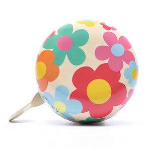 May include: A cream-coloured bicycle bell featuring a vibrant floral design. The flowers are in red, pink, orange, blue, and green, with yellow centres. It has a matching cream-coloured lever.
