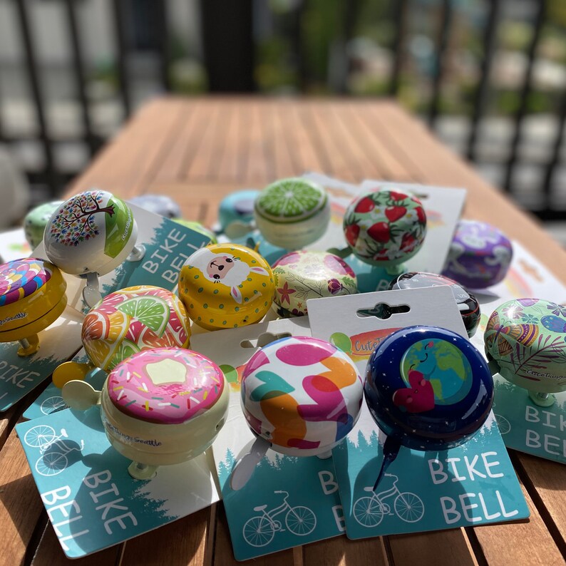group of cute bike bells with packaging 

cute bike accessories - bicycle accessory - gift for her - gift for bike rider - birthday gift - bicycle bell - Cute Things Seattle bike bell - cycling gifts, holiday gifts, wheelchair accessories