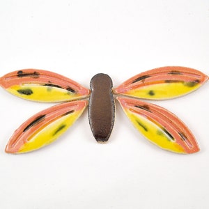 May include: A ceramic dragonfly mosaic tile with yellow, orange, and black accents. The dragonfly has a brown body and four wings.
