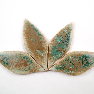 May include: Four ceramic leaf-shaped tiles with a green and brown glaze. The glaze has a speckled and crackled effect.