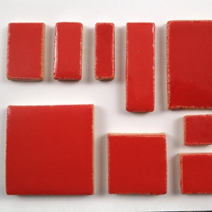 Pode incluir: Conjunto de azulejos de cerâmica vermelhos em vários tamanhos e formas. Os azulejos são lisos e têm um acabamento brilhante.