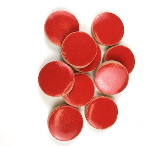 May include: A group of ten red ceramic tiles, each with a smooth, glossy finish. The tiles are round and have a slightly raised edge.