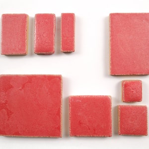 May include: Assortment of six pink ceramic tiles in various sizes and shapes. The tiles have a textured surface and a slightly uneven edge.