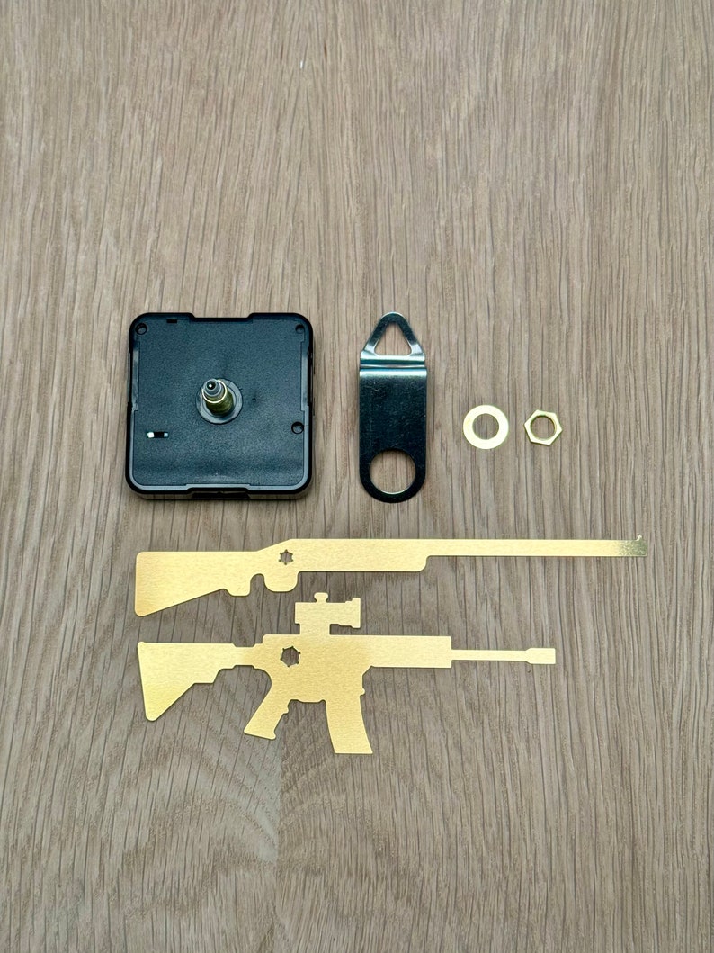May include: Clock kit with gold metal cutouts of two rifles, a black clock mechanism, a black metal hanger, and two gold metal mounting hardware pieces.