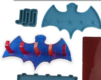 Op de afbeelding: Een set van vijf siliconen mallen voor het maken van een vleermuisvormige wandhaak. De mallen zijn blauw en rood en bevatten een mal voor het vleermuislichaam, een mal voor de vleermuisvleugels en een mal voor de haken. De mallen zijn gemaakt door Silicone.City.