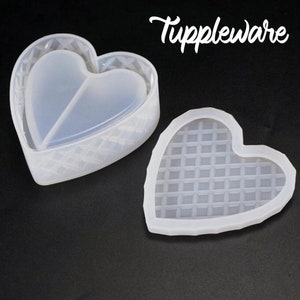 May include: Two clear silicone heart-shaped molds, one with a divided heart inside and the other with a waffle pattern. The molds are for making resin crafts.