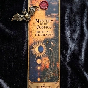 May include: A rectangular bookmark with the text "Mystery of the Cosmos" and "Delve into the Unknown". It features a bronze bat charm and a red wax seal. The artwork depicts celestial bodies and a robed figure.