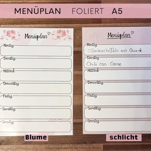 May include: A printable meal planner with a floral design. The planner has a pink and white colour scheme and includes the days of the week. The text "Menüplan" is written in a cursive font. The planner is labelled "Blume".