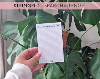 May include: A white sheet of paper with a grid of 100 circles. Each circle has a number printed inside. The text "Kleingeld Sparchallenge" is at the top of the sheet. The text "Kleinvieh macht auch Geld" is in the middle of the sheet. The text "20 €" is at the bottom of the sheet.