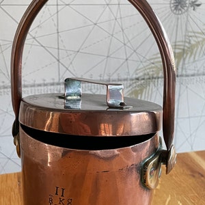 May include: A copper bucket with a hinged lid and a handle. The bucket has a brass latch and is marked with the inscription "II TK COLE 1966".