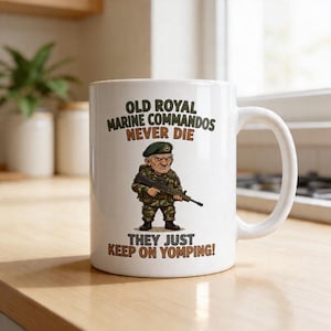 May include: White ceramic mug featuring a cartoon illustration of a Royal Marine Commando holding a rifle. The mug has text that reads "OLD ROYAL MARINE COMMANDOS NEVER DIE THEY JUST KEEP ON YOMPING!"