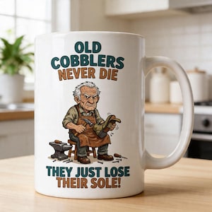 Puede incluir: Taza de cerámica blanca con una ilustración de dibujos animados de un zapatero y el texto "OLD COBBLERS NEVER DIE THEY JUST LOSE THEIR SOLE!" en verde azulado y marrón. La taza tiene un asa.