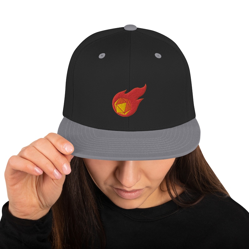 May include: A black and gray baseball cap with a red and yellow embroidered design of a flaming dice.