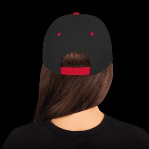 May include: Black and red baseball cap with a red strap in the back. The cap is made of a soft, breathable fabric.