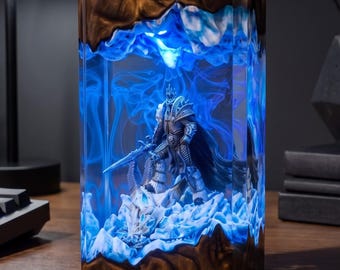 May include: A rectangular resin lamp featuring a dark brown, swirling wood-like base and top. The center contains a miniature armored warrior figure standing on a jagged, icy blue landscape, illuminated by a bright blue internal light.