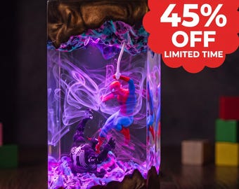 May include: A rectangular resin lamp featuring a scene with Spider-Man and Venom figures encased in clear material with purple and white swirling smoke effects, framed by textured bronze-colored top and bottom sections with a red promotional badge.
