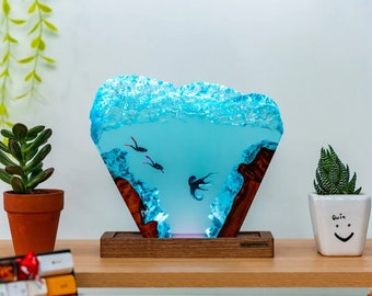 Könnte beinhalten: Eine blaue Harzskulptur, die eine Unterwasserszene mit zwei Tauchern und einer Qualle darstellt. Das Harz ist auf einem Holzsockel mit dem Aufdruck "Seaworthy" befestigt.