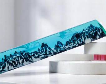 Può includere: Un cilindro trasparente blu chiaro con un design a spirale bianco e nero all'interno. Il cilindro poggia su una superficie bianca.