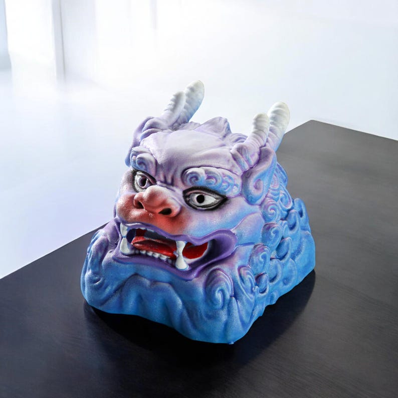 Pu&ograve; includere: Una scultura in ceramica blu e viola di una creatura mitologica con un'espressione feroce. La scultura ha una superficie testurizzata ed &egrave; decorata con dettagli intricati.