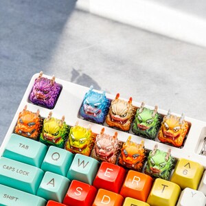 Pu&ograve; includere: Una tastiera con tasti colorati che presentano un design a forma di drago. I tasti sono disposti in un motivo arcobaleno, con ogni tasto che presenta un colore diverso. La tastiera ha una base bianca e tasti neri.
