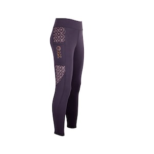 Può includere: Leggings viola con una tasca a fantasia sulla coscia sinistra. La tasca ha un logo dorato che dice "CAK".