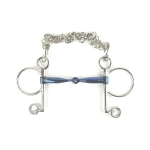 Könnte beinhalten: Ein Pferdemaul mit blauem Mittelteil und silberfarbenen Ringen und Kette. Das Gebiss hat ein gebogenes blaues Mundstück und ist für den Einsatz im Reitsport konzipiert. Das Metall ist glänzend und reflektiert das Licht.