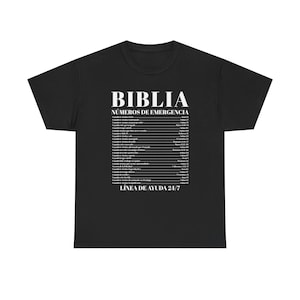 Puede incluir: Camiseta negra con texto blanco. La camiseta presenta la palabra "BIBLIA" sobre "NÚMEROS DE EMERGENCIA" y una lista de números de emergencia. Debajo de la lista está el texto "LÍNEA DE AYUDA 24/7".