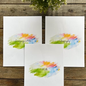 May include: Three white sheets of paper with colourful watercolour backgrounds. The top sheet says "Geography", the middle sheet says "Math", and the bottom sheet says "Language Arts".