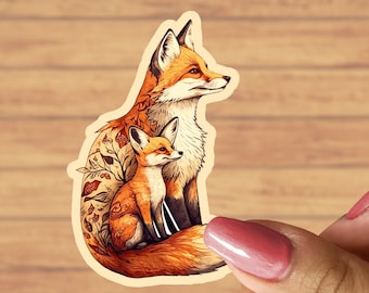 May include: A sticker featuring a detailed illustration of a mother fox and her cub. The mother fox is sitting with her tail curled around her cub, and both foxes have orange fur with white accents. The sticker has a white background and is perfect for adding a touch of nature to any surface.