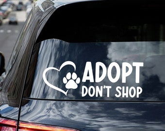 May include: A black car with a white sticker on the back window that says "Adopt Don't Shop" with a paw print inside a heart.