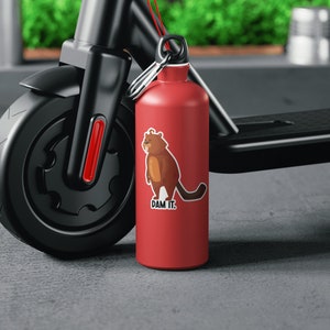 May include: A red water bottle with a black and brown cartoon animal sticker that says "DAM IT." The bottle is attached to a black electric scooter.