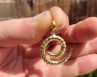 Op de afbeelding: Een gouden hanger in de vorm van een spiraal met een getextureerd oppervlak.