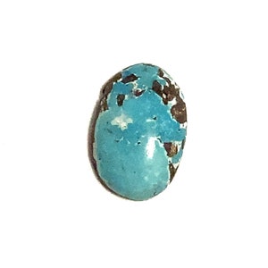 A bright blue polished oval shaped loose gemstone with brown and white markings. It has a rounded top with a flat underside. the picture has been taken of the top of the stone with a plain white background