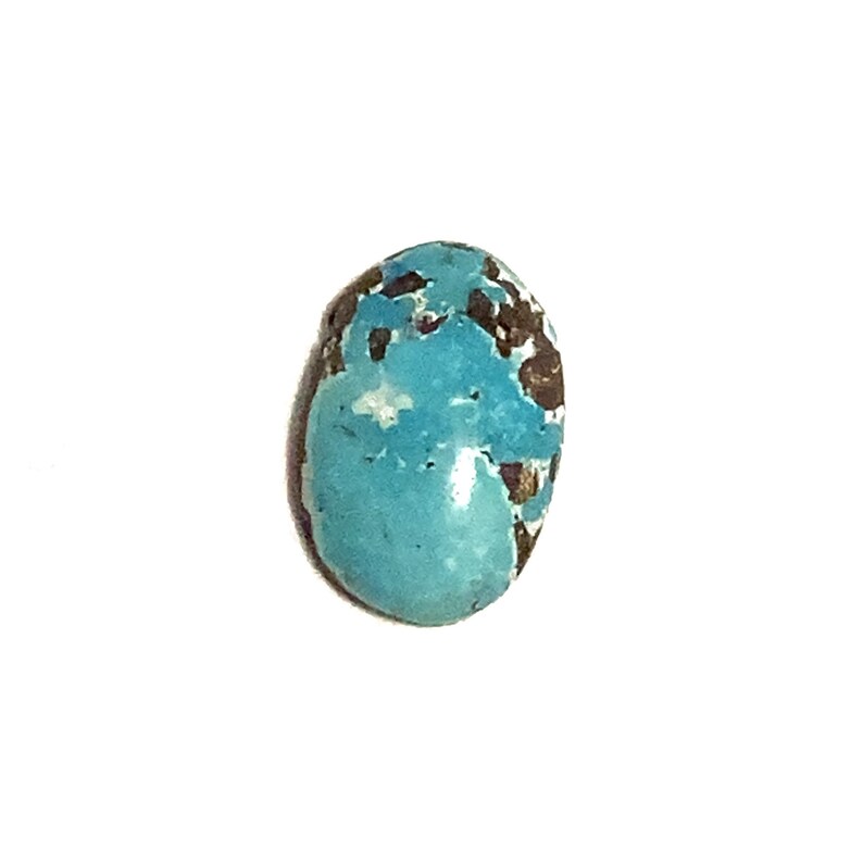 A bright blue polished oval shaped loose gemstone with brown and white markings. It has a rounded top with a flat underside. the picture has been taken of the top of the stone with a plain white background